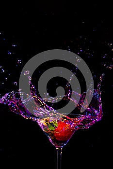 Strawberry in Whine Glass Along With Droplets Colorful Liquid. Isolated Over Black. Vertical Image