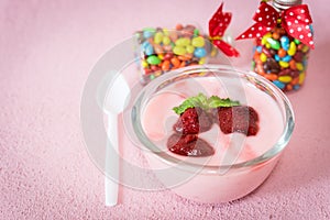 Strawberry yogurt with strawberry  on Baby Gift Colorful candies in jar on table pink background. strawberry yoghurt. pink yogurt photo