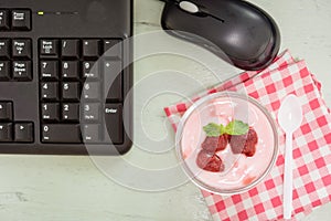 Strawberry yogurt on desk with mount keyboard