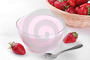 Strawberry yogurt in a glass bowl with strawberries on a white background