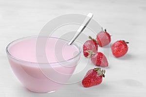 Strawberry yogurt in a glass bowl with strawberries on a white background