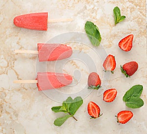 Strawberry yogurt ice cream popsicles with mint over marble tray