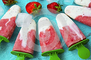 Strawberry and yogurt popsicles with fruits on blue summer background