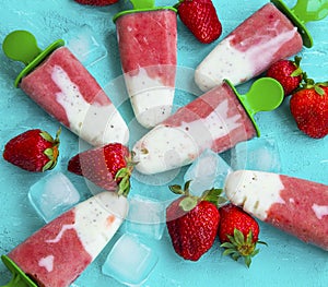 Strawberry and yogurt popsicles with fruits on blue summer background