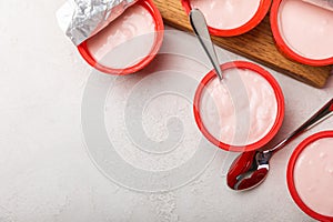 strawberry yogurt in a red plastic cup with a spoon on background.