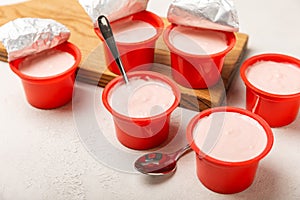 strawberry yogurt in a red plastic cup with a spoon on background.