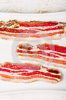 Streaky bacon with on the white plate vertical