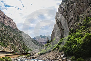 Stream beside built up highway through towering cliffs of Rocky Mountains