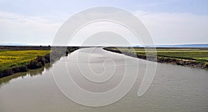 a stream with colored fields around it flows into the sea photo