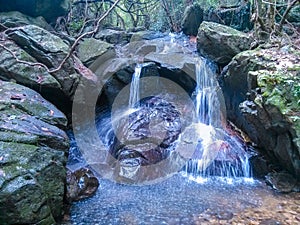 A stream flowing from a crevice in the top of a mountain.