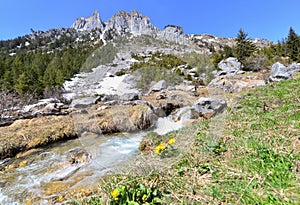 Stream flowing down on rocky peak mountains