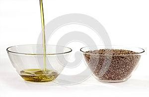 A stream of flowing hemp seed oil and hemp seeds in a round glass bowls.