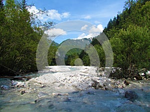 Stream flowing through rock alluvium and willow trees