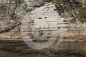 Stream flowing by a rock wall, winter