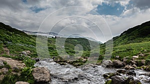 The stream flows through a rocky bed in the valley.