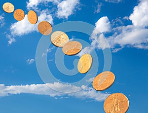 Stream of gold coins falling from blue sky