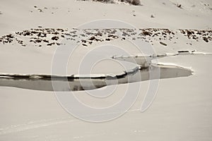 A stream meandering through a snow-covered plain photo