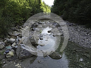 Stream in a natural area in Upper Bavaria with barrages and large stones at sunrise