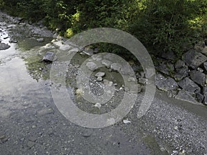 Stream in a natural area in Upper Bavaria with barrages and large stones at sunrise