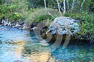 Stream pool of a small mountain river with a beautiful rock on the bank