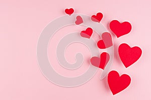 Stream of red paper hearts on soft pink color background, copy space. Valentines day art.