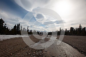 Stream running through gravel riverbed under lenticular clouds in the spring in Denali National Park in Alaska USA