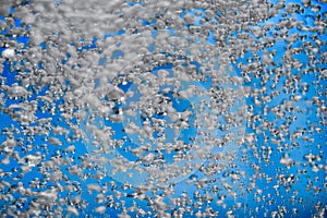 A stream of shiny air bubbles illuminated by light and shining on a blue background. Close up of light lit oxygen