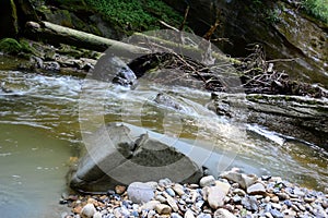 The stream of a small waterfall flows down the rock onto the stones. Natural background of the surrounding environment