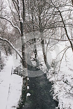 Stream surrounded by trees and roads covered in snow during storm Emma.