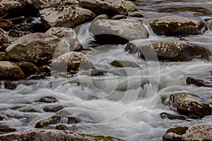 Stream with touches of blue reflections, fall leaves, water flowing over rocks