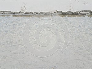 Stream of water at beach eroding sand and foot print