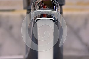 Stream of water falling from a faucet in a sink