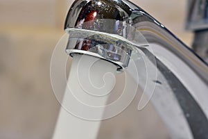 Stream of water falling from a faucet in a sink photo