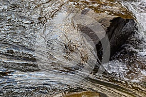 The stream of water flowing over rocks.Image close-up