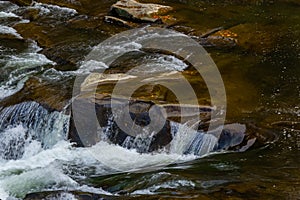 The stream of water flowing over rocks.Image close-up