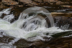 The stream of water flowing over rocks.Image close-up