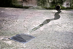 Stream of water flows into the drain hatch after rain