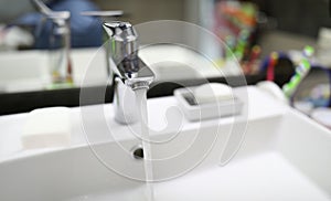 Stream water flows from faucet into bathroom sink