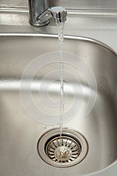 Stream of water flows from an open chrome tap