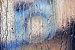 Stream of water in heavy rain. Raindrops on window pane.