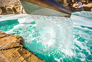 Stream water out of artificial waterfall in outdoor pool