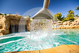 Stream water out of artificial waterfall in outdoor pool