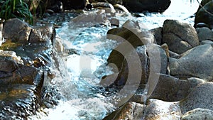 Stream water in rapid river in mountain close up. Water stream quickly flowing in rocky river. Fast flowing water stream