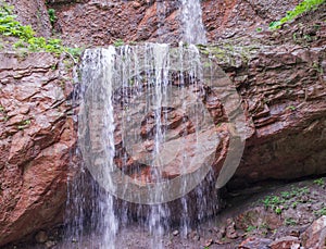 Stream waterfall flowing from the red rocks.