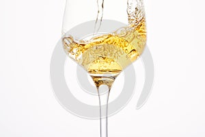 Stream of white wine flows into stem glass, swirls.