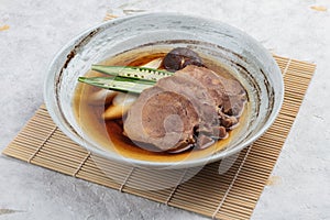 Streamed beef tounge gyutan served with shiitake, Japanese scallion and chilli with soup in rounded stone plate on makisu.