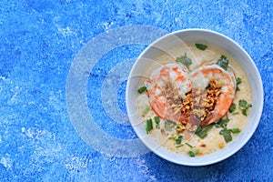 Streamed eggs topping with shrimps, cilantro and fried garlic on blue background