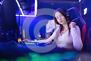 Streamer beautiful girl professional gamer smile playing online games computer with headphones, neon color