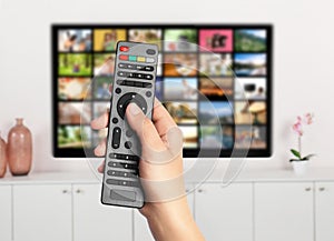 Streaming video services. Woman using remote control to change channels on TV