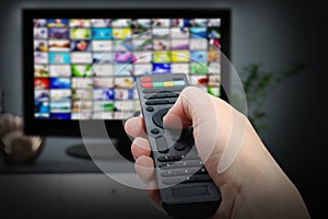 Streaming video services. Woman using remote control to change channels on TV